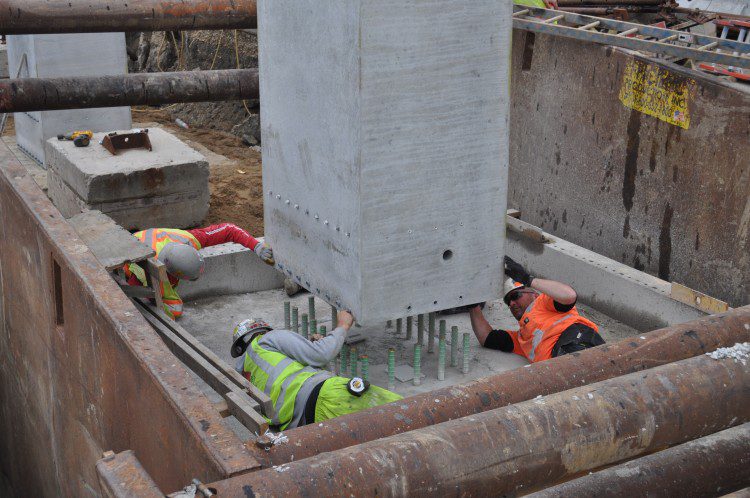 A precast column is carefully set in place on top of new footings (top), saving time in the sequencing of construction. 